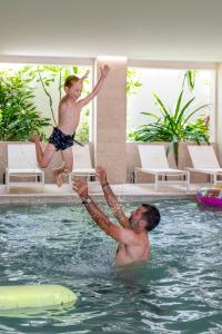 a man and a boy jumping in a swimming pool at Hôtel Helios & SPA - Ile des Embiez in Six-Fours-les-Plages