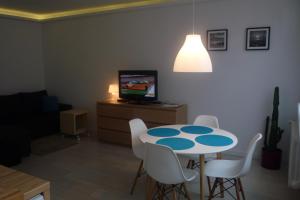 Mieszkanie Przy Plaży في غدانسك: غرفة معيشة مع طاولة وكراسي وتلفزيون