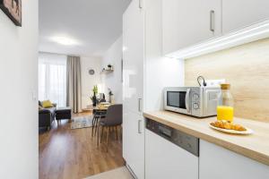 een witte keuken met een magnetron en een tafel bij Marina apartment at Danube - FREE PRIVATE PARKING! in Boedapest