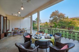 a dining room with a table and chairs on a balcony at SaffronStays Mograa laffaire in Alibaug