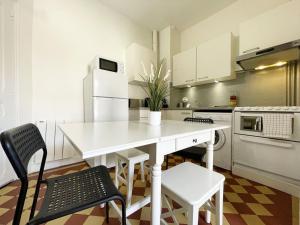uma cozinha branca com uma mesa e cadeiras brancas em Au fil de l’Eure, quartier authentique et plein de charme em Chartres