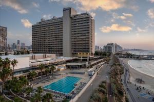 ein großes Gebäude mit einem Pool vor einer Stadt in der Unterkunft The Vista At Hilton Tel Aviv in Tel Aviv