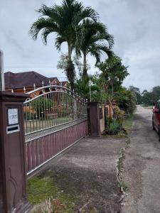 a red fence with a palm tree behind it at Rumah Teratak Bonda in Jertih