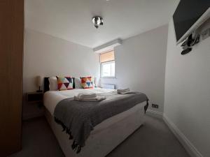 a white bedroom with a bed with a window at Apt 3, Soho Apartments 2nd & 3rd floors by Indigo Flats in London