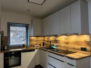 a kitchen with white cabinets and a wooden wall at Pension Hintergarten in Oberzeiring +8 photos