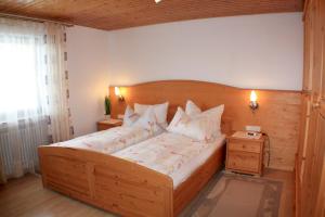 um quarto com uma grande cama de madeira com almofadas brancas em Schlosshof - der Urlaubsbauernhof em Elzach