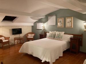 um quarto com uma cama branca e uma televisão em Posada Mellante em Pechón