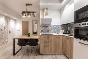 a kitchen with white cabinets and a wooden island with stools at Bilbao Park III with parking by Aston Rentals in Bilbao