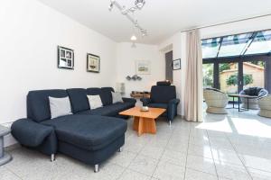 ein Wohnzimmer mit einem Sofa, Stühlen und einem Tisch in der Unterkunft Ferienhäuser Deichkrone in Bensersiel