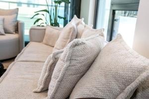 a pile of pillows sitting on top of a couch at High End 1BD Beach Apartment in Tel Aviv