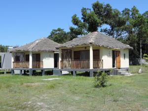 two houses with thatched roofs in a field at LE SERENITY LODGE in Mahanoro