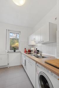 a white kitchen with a sink and a dishwasher at Stadt-Apartment 3 Zimmer mit Terasse in Hannover