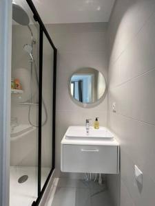 een witte badkamer met een wastafel en een spiegel bij Cosy flat for 6 people #2 in Asnières-sur-Seine