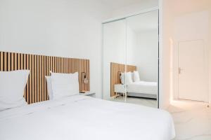een witte slaapkamer met een groot bed en een spiegel bij Cosy flat for 6 people #2 in Asnières-sur-Seine