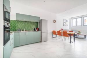 een keuken met groene kasten en een tafel met stoelen bij Cosy flat for 6 people #2 in Asnières-sur-Seine