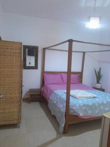 a bedroom with a canopy bed with pink pillows at Pied a terre in Ouakam in Ouakam