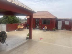 een rood huis met een patio met een tafel bij Keur Karim sarr chambre d hôtes in Mbour