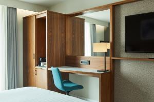 - une chambre avec un bureau, une chaise et une télévision dans l'établissement Courtyard by Marriott London Gatwick Airport, à Horley