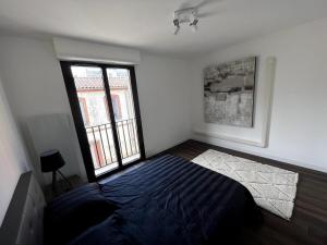 a bedroom with a bed and a large window at Sublime T2 avec balcon in Montauban