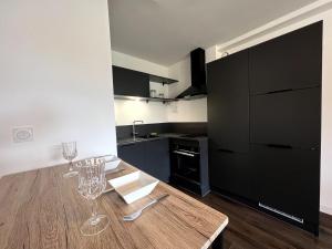 eine Küche mit einem Holztisch mit Weingläsern darauf in der Unterkunft Sublime T2 avec balcon in Montauban