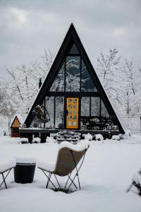 a house covered in snow with two chairs in front of it at Porumbacu Garden in Porumbacu de Sus