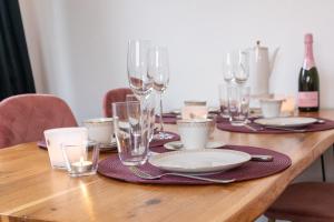 a wooden table with wine glasses and plates on it at Dat Huuske - das besondere Ferienhaus in Salzhausen