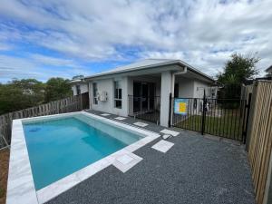 a house with a swimming pool in front of a fence at Upper Coomera Castle 1 in Gold Coast