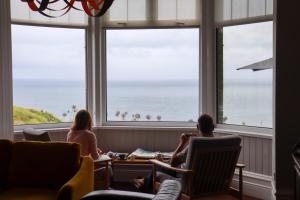 people sitting in chairs in a room with a view of the ocean at Housel Bay Hotel in Lizard