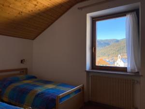 a bedroom with a bed and a large window at Casetta Turati in Castelfondo