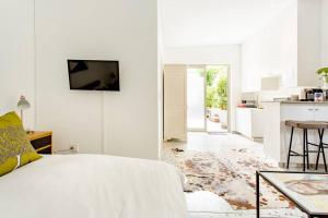 1 dormitorio blanco con 1 cama y cocina en Orchard Lane en Ciudad del Cabo