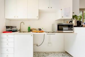 a white kitchen with white cabinets and a microwave at Orchard Lane in Cape Town