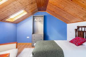 a room with a bed with blue walls and wooden ceilings at A casa de Valenza 