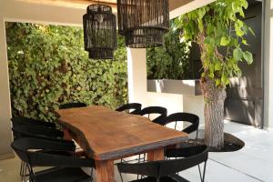 een houten tafel met zwarte stoelen en een plant bij Heura Petit Hotel in Ciudad Lujan de Cuyo