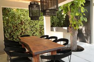 una mesa de madera con sillas negras y una planta en Heura Petit Hotel en Luján de Cuyo