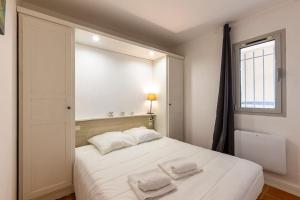 um quarto com uma cama branca com duas toalhas em La Ciotat Appartement T2 piscine clim parking em La Ciotat