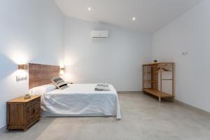 een witte slaapkamer met een bed en een houten kast bij MalagaSuite Villa Nomada El Torcal in Antequera