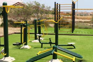 a playground with yellow and green equipment on a green field at Двухкомнатные апартаменты в жилом комплексе Caesar Beach D2 Flat11 in Boğaz