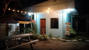 um banco em frente a uma casa com um guarda-chuva em ELEN INN - Malapascua Island - Private Fan room with shared bathroom #5 em Malapascua