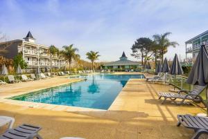 una gran piscina con sillas y sombrillas en Howard Johnson Hotel & Convention Center Madariaga - Carilo, en Cariló