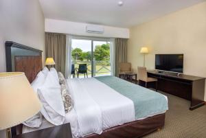 カリロにあるHoward Johnson Hotel & Convention Center Madariaga - Cariloのベッドと机とテレビがあるホテルの部屋