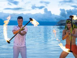 un hombre y una mujer de pie en la playa con palos de fuego en Sofitel Kia Ora Moorea Beach Resort en Maharepa