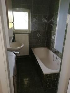 a bathroom with a bath tub and a sink at Rooming Green Weyregg in Weyregg