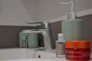 a bathroom sink with a faucet and some cosmetics at La Garde de la Tonnellerie in Chartres