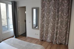a bedroom with a bed and a mirror and a window at La Garde de la Tonnellerie in Chartres
