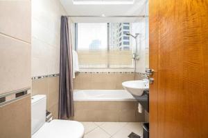 a bathroom with a tub and a toilet and a sink at Trident Grand Residence,Dubai Marina - 3BR Apartment - Allsopp&Allsopp in Dubai