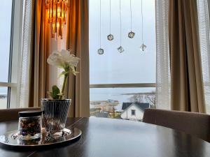 une table avec un vase devant une fenêtre dans l'établissement Hotel Frøya, à Sistranda