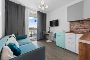 a living room with a blue couch and a kitchen at RentPlanet - Apartamenty Wiktoryn in Warsaw
