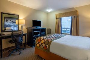 a hotel room with a bed and a desk and a computer at Super 8 by Wyndham Edmonton International Airport in Leduc