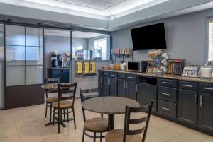 a kitchen with two tables and a bar with a tv at Super 8 by Wyndham Edmonton International Airport in Leduc