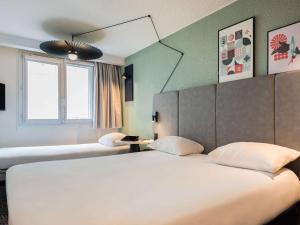 パリにあるイビス パリ イタリー トルビアックのベッド2台と鏡が備わるホテルルームです。